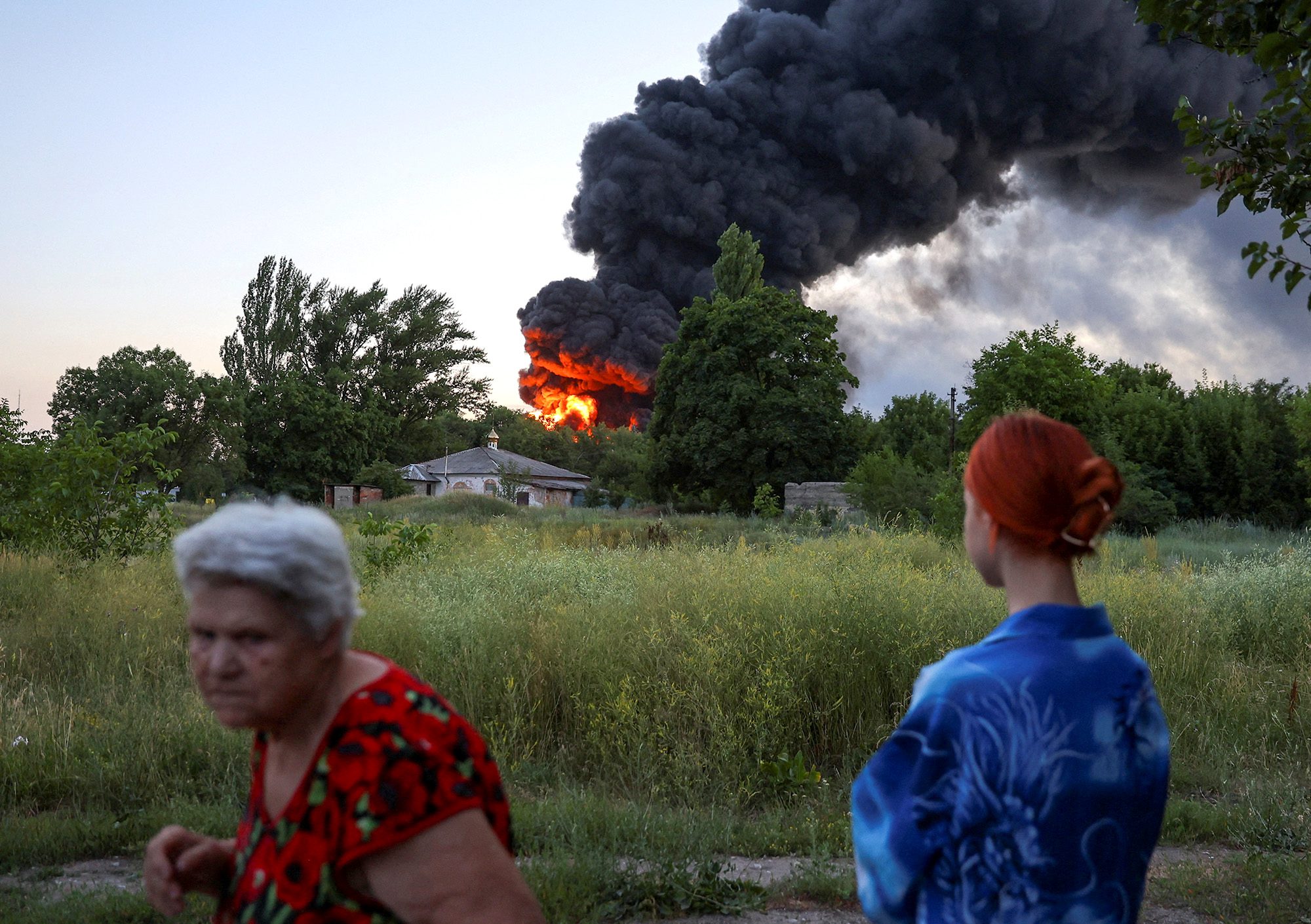 Местные жители смотрят на дым, поднимающийся после взрыва в Донецке, Украина, 7 июля.